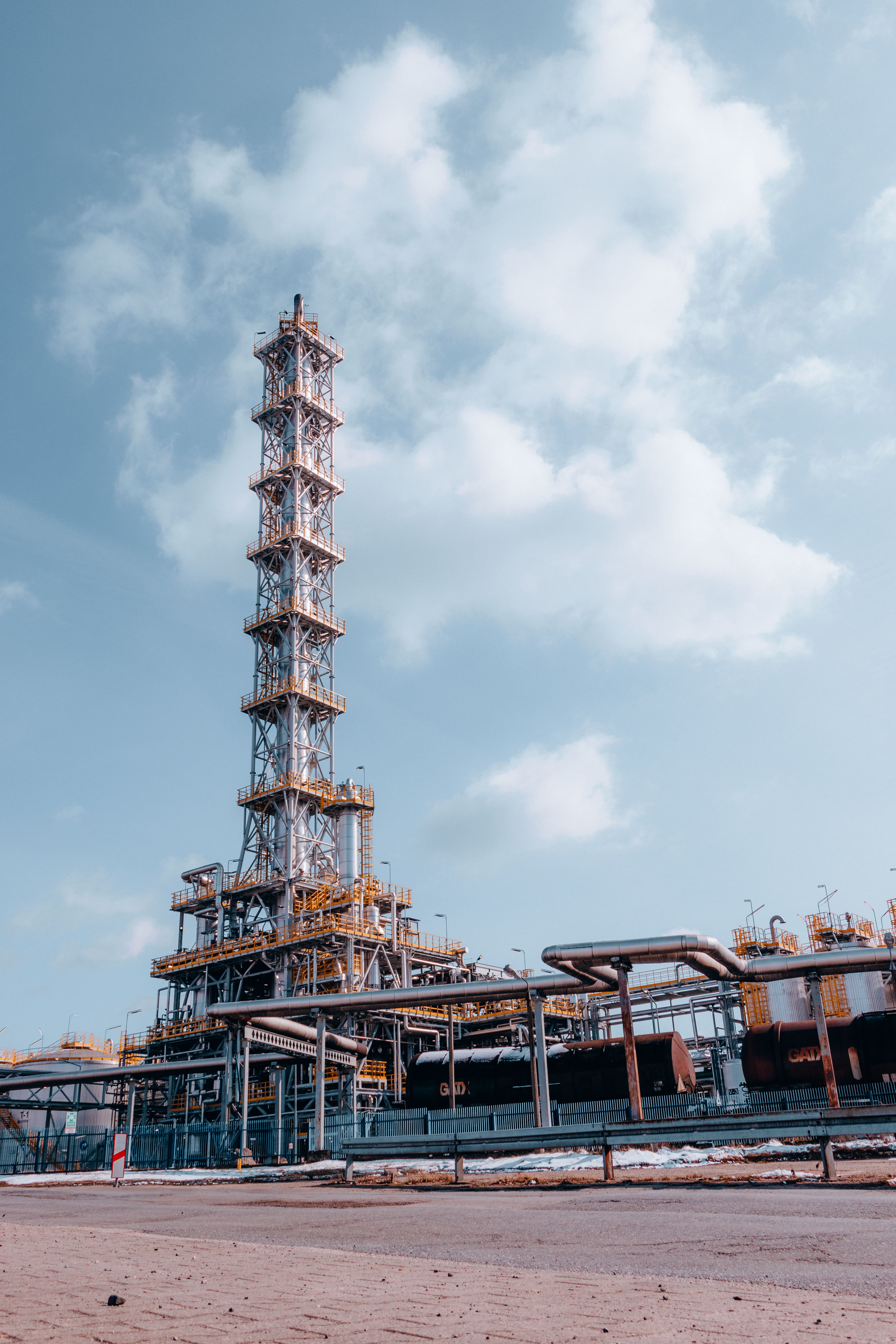 Tall process tower and industrial piping in an energy facility