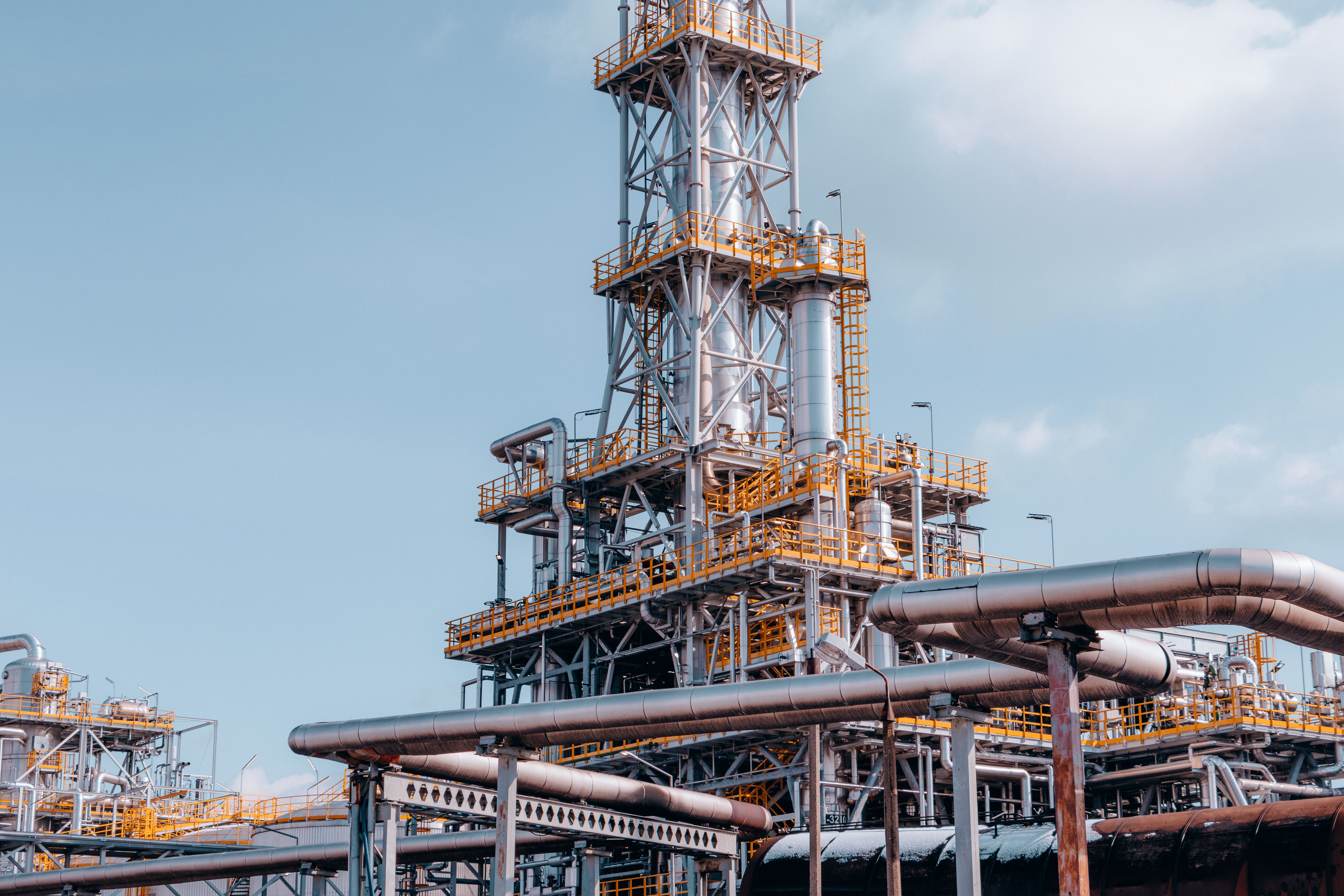 Detailed view of process equipment, pipe racks, and a tall industrial column