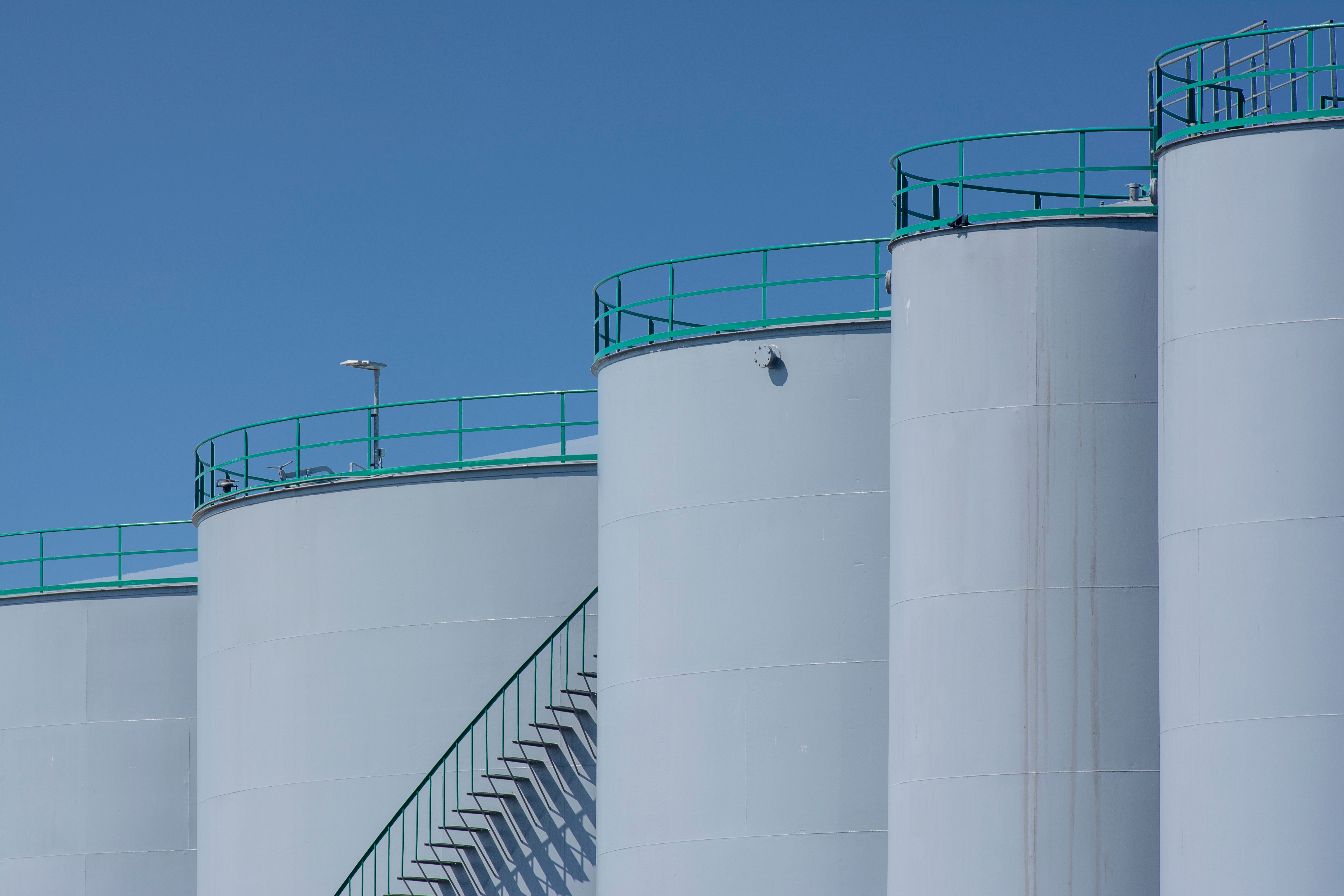 Large industrial storage tanks under a clear blue sky